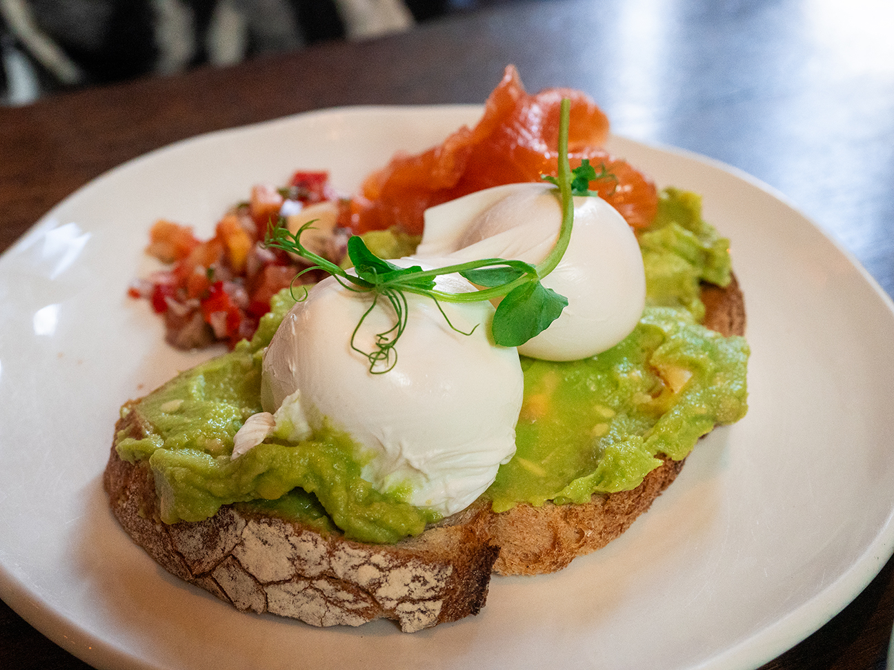 Smashed avocado toast with poached eggs smoked salmon and chilli salsa